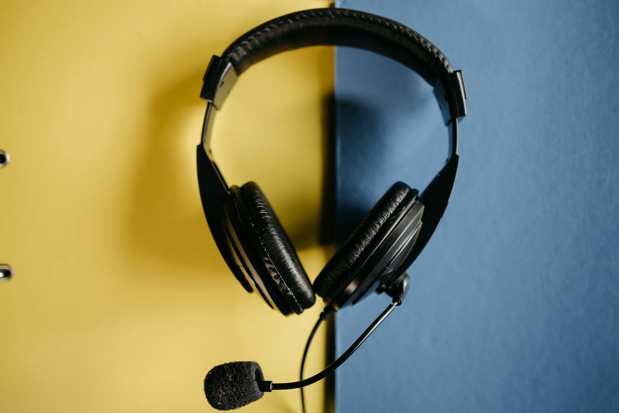 Close-up of a black headset with microphone on a contrasting yellow and blue backdrop.
